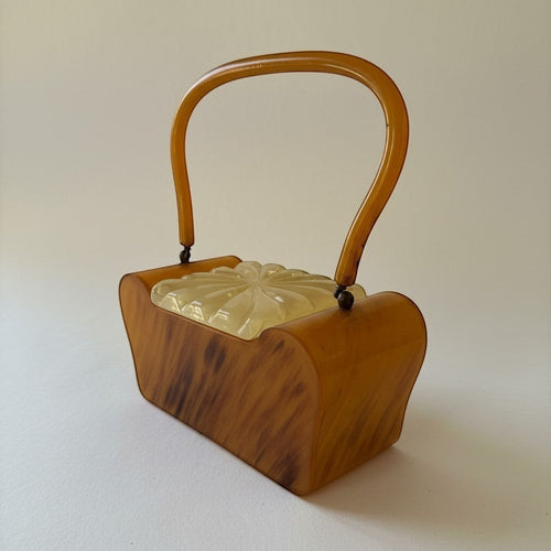 Atlas & Arden vintage 1950s butterscotch marbled Bakelite box purse with carved pearlized cream Lucite lid and arched handle.